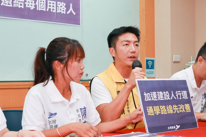 交通安全共同政見記者會，出席者手持「加速建設人行道 通學路線先改善」手板發言